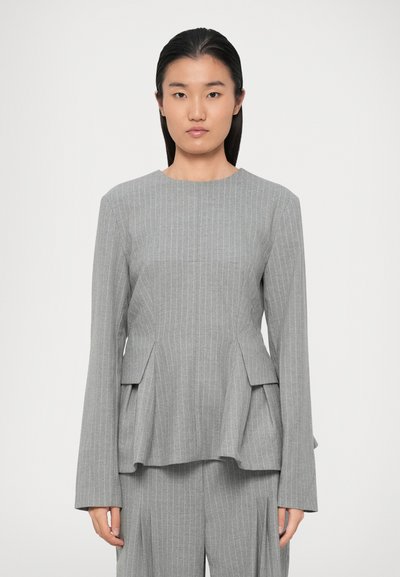 Gray peplum top with long sleeves, vertical pinstripes, and a round neckline. Features two flap pockets at the waist and a flowy texture.