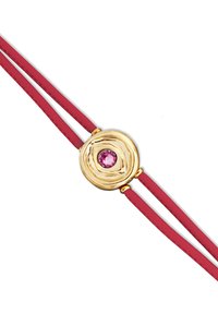 Colgante circular en tono dorado con superficie texturizada, que presenta una piedra preciosa rosa en el centro, unido a dos cordones de cuero rojo.