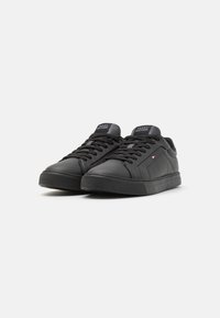 Czarne skórzane sneakersy o gładkim wykończeniu, z płaskimi czarnymi sznurowadłami, gumową podeszwą i logo na języku.