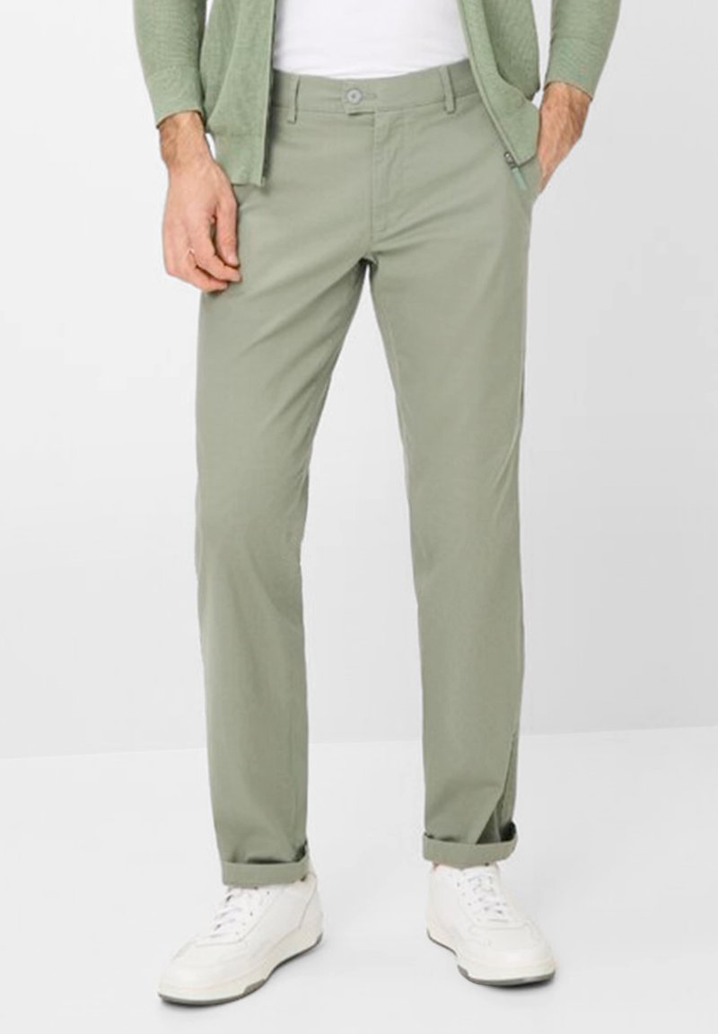 Light green, cotton trousers with a straight fit, front button closure, and rolled cuffs, paired with white sneakers.