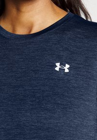 Granatowy t-shirt z krótkim rękawem wykonany z teksturowanej tkaniny, z małym białym logo Under Armour na lewej stronie klatki piersiowej.