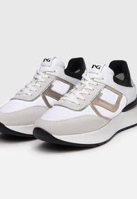 Białe i beżowe sneakersy wykonane z połączenia skóry i zamszu. Posiadają czarne akcenty, szary pasek oraz logo na języku.