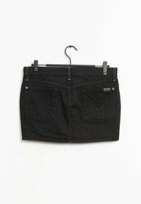Gonna mini in denim nero con cinque passanti per cintura, due tasche posteriori e cuciture sottili. Appesa a una gruccia in metallo nero su uno sfondo bianco.