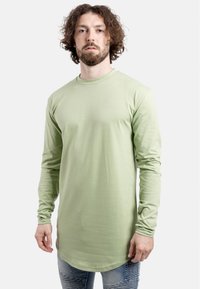 Langsleeve shirt in lichtgroene stof met een ronde hals, met een relaxte pasvorm en een licht gebogen zoom, gecombineerd met versleten jeans.