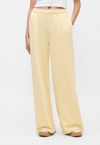 Απαλά κίτρινα, παντελόνια με φαρδιά γραμμή κατασκευασμένα από μαλακό ύφασμα με ελαστική μέση και πλαϊνές τσέπες, που διαθέτουν λεία υφή και χαλαρή εφαρμογή.