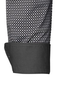 Polsino di camicia a fantasia bianca e nera, con un motivo a diamante. Tessuto morbido e liscio con un bordo nero solido a contrasto sul polsino.