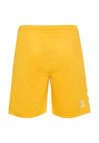 Gele sportshorts met een elastische tailleband, met een gladde textuur en een wit chevronpatroon aan de zijkanten. Merkenlogo aan de rechteronderkant.