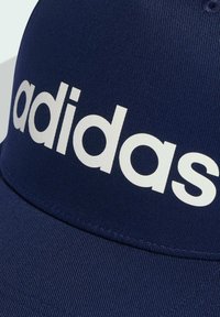 Gorra de béisbol azul marino con una textura estriada y un gran logo blanco de "adidas" en la parte frontal. Tiene un visor curvado y detalles cosidos.