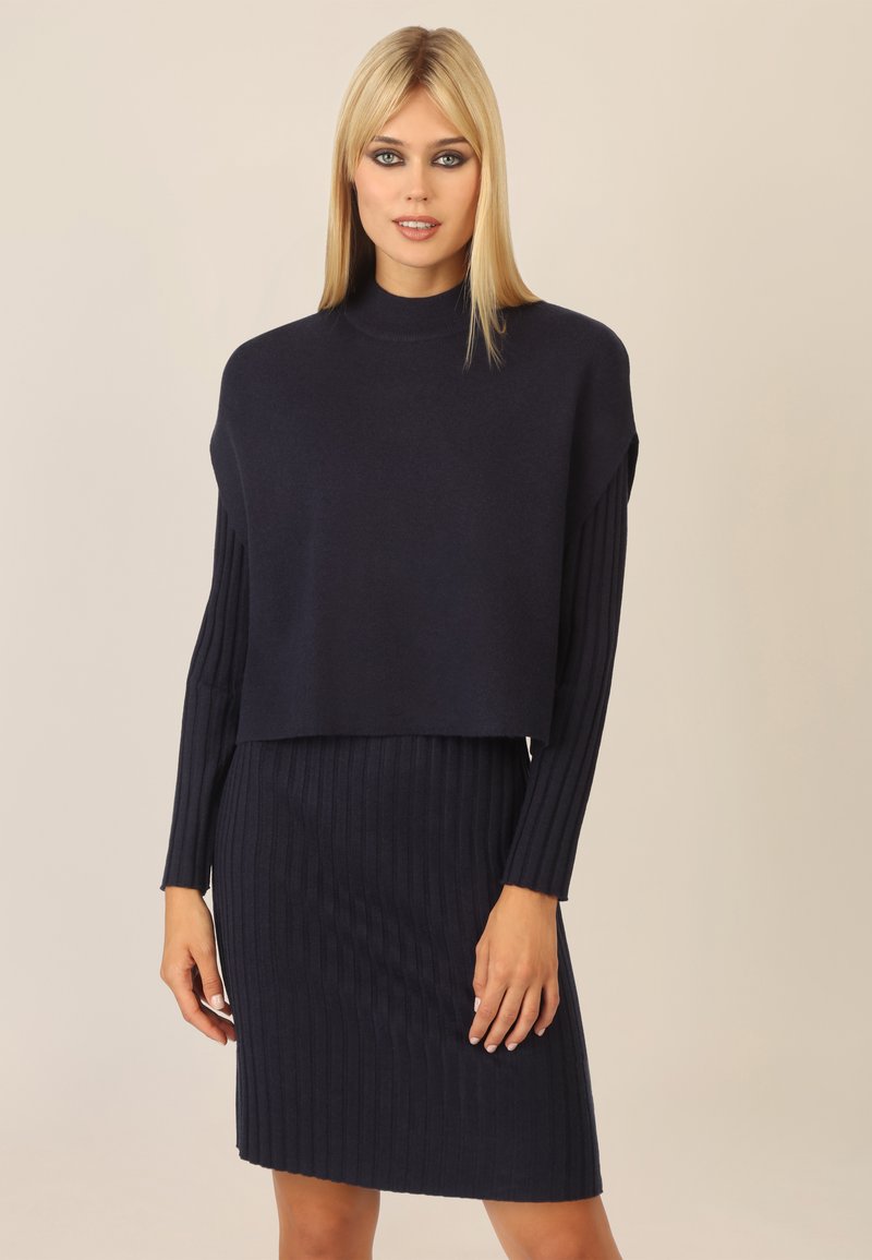 Navyblaues Strickkleid mit einem cropped, weit geschnittenen Oberteil und einem gerippten, figurbetonten Rock. Weicher Stoff mit nahtlosem Design.