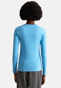 Light blue long-sleeve t-shirt made from soft fabric, featuring a round neckline and a slim fit, with a tag on the lower side.