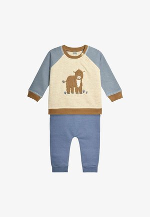 Katoenen peuteroutfit met een lichtbeige sweatshirt met een bruin koeienontwerp en blauwe mouwen, gecombineerd met blauwe broeken.