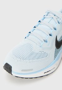 Baskets de course bleu clair avec une tige en mesh respirant, logo swoosh noir, détails texturés et semelle blanche rembourrée avec le marquage "AIR ZOOM".