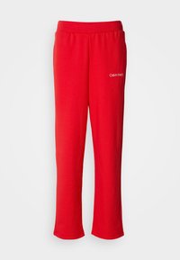 Czerwone bawełniane spodnie dresowe z elastycznym pasem i luźnym krojem. Posiadają małe białe logo "Calvin Klein" po lewej stronie na dole.