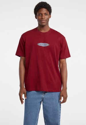 Bordo pamučna majica kratkih rukava s okruglim izrezom, s crno-bijelim logotipom "GUESS JEANS" na prednjoj strani.