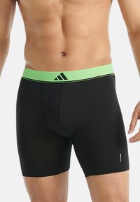 Miestenske čierne boxerky s elastickým zeleným pásom zdobeným pruhmi a logom. Vyrobené z hladkej, elastickej tkaniny pre pohodlie.