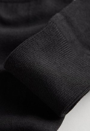 Sort strikstof med en glat tekstur, der har en ribbet manchet og rene kanter. Nærbillede fremhæver fine stikningsdetaljer.