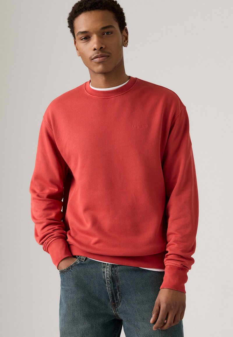 Rode katoenen sweatshirt met ronde hals, geribbelde manchetten en geborduurd logo. Draag het over een wit shirt, gecombineerd met blauwe jeans.