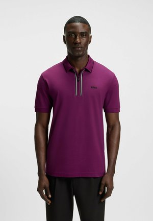Lila Poloshirt mit kurzen Ärmeln, Reißverschlusskragen, schwarzem Logo und kontrastierenden Streifen am Kragen. Glatte Stoffstruktur.