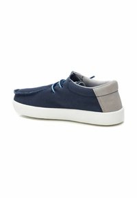 Zapato de lona azul marino con tacón de ante gris, suela blanca y cordones azules. Presenta una punta redondeada y un diseño minimalista.