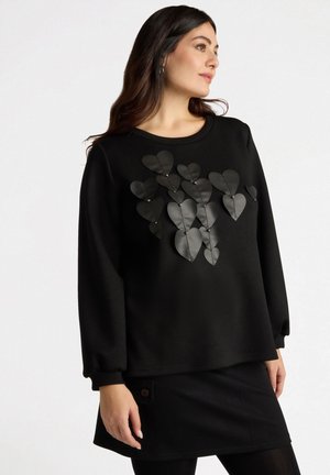 Sweatshirt noir à col rond, doté d'appliqués en cuir en forme de cœur superposés et d'accents métalliques. Manches longues avec poignets.