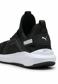Sort Puma sneakers har en mesh-overdel, teksturerede paneler, en polstret hvid sål og branding på hælen og siden.