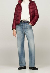 Bordowa pikowana kurtka, kremowy sweter z dzianiny, jasnoniebieskie jeansy o prostych nogawkach, czarny pasek i czarne buty. Teksturowany, nowoczesny, casualowy strój.