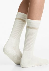 Knee-lange crèmekleurige sokken met ribbelstructuur en een beige strook near de bovenkant. Zacht materiaal en gevoerde zolen.