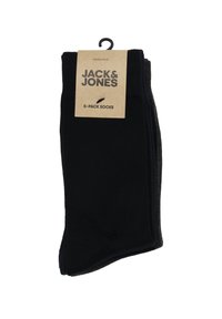 Cinq paires de chaussettes noires, en mélange de coton, avec un design simple. Emballées avec une étiquette en carton brun indiquant la marque et la quantité.