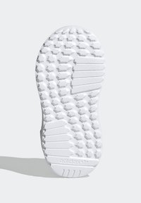 Vit gummisula med ett hexagonalt mönster och texturerade områden. "adidas"-logotypen är prägling nära hälen.