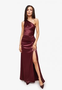 Bordó saténové šaty s jedním ramenem, s nařasenými detaily, bočním rozparkem a dlouhou délkou až na zem. Doplněné o ladící lodičky a náramek.