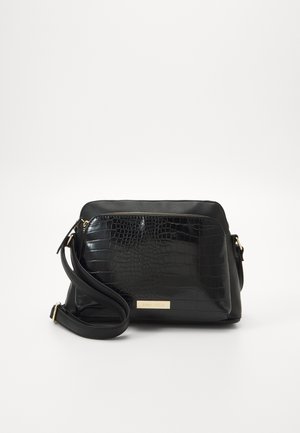 Zwarte crossbodytas met verstelbare riem, voorvak met krokodillenstructuur, en gouden rits en merkplaatje op effen achtergrond.