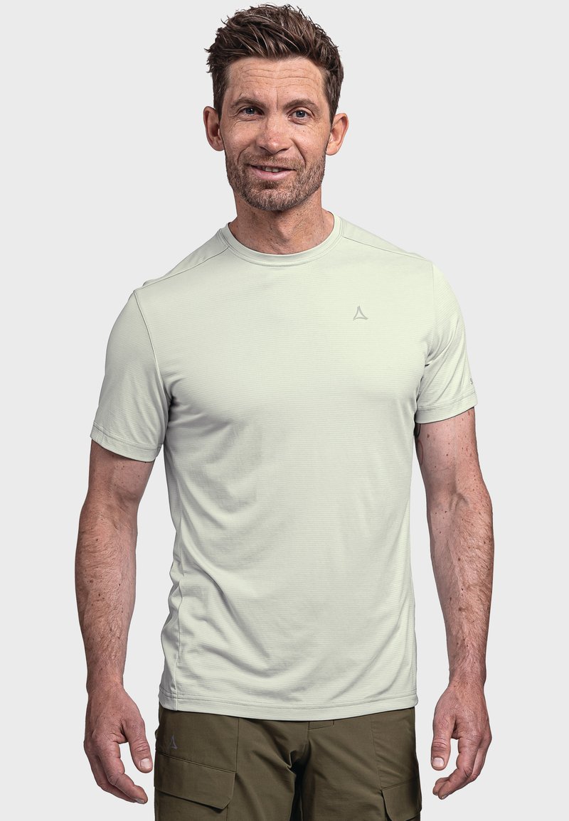 Hellgraues sportliches T-Shirt mit kurzen Ärmeln, rundem Ausschnitt, strukturiertem Stoff und dezentem Logo auf der Brust. Kombination mit olivgrünen Hosen.