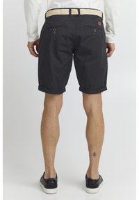 Shorts noirs à revers, fabriqués dans un tissu léger. Comprend deux poches arrière avec des fermetures à bouton et une ceinture en tissu texturé.