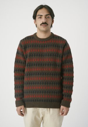 Brown knitted sweater featuring a pattern of red and navy blue shapes. Ribbed crew neckline and cuffs. Soft texture. Straight fit design.