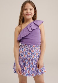 Paarse top met één schouder en ruches, gecombineerd met een gelaagde rok in een veelkleurig ruitpatroon met oranje, blauwe en paarse tinten.