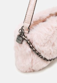Różowa torebka ze sztucznego futra z łańcuszkowym paskiem. Posiada teksturowaną powierzchnię oraz małą metalową zawieszkę z logo "GUESS".