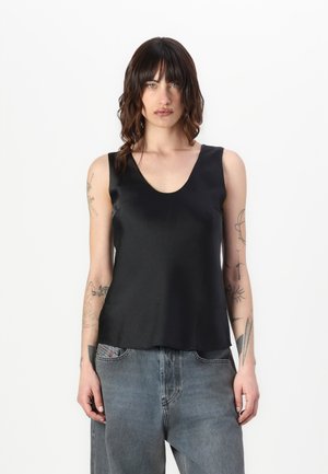 Svart satin cami med rund hals og uten ermer. Glatt tekstur, noe utvidet kant, brukt sammen med lyse denimjeans.