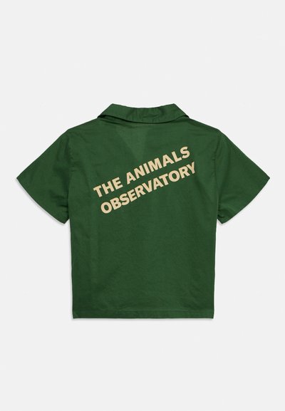 Σκούρο πράσινο κοντομάνικο πουκάμισο με γιακά, με μπεζ κείμενο "THE ANIMALS OBSERVATORY" διαγώνια στην πλάτη.