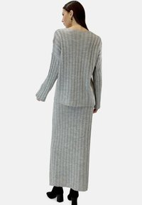 Grå randig långärmad tröja och matchande maxikjol, med en mjuk textur och avslappnad passform, bärs med svarta ankelboots.