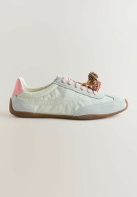 Baskets gris clair avec talon rose, lacets roses et deux pompons marron attachés sur le dessus, avec une semelle en caoutchouc marron.