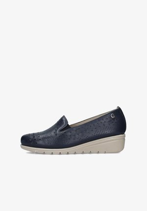 Scarpa slip-on in pelle traforata blu navy con suola beige a zeppa e piccolo logo metallico vicino al tallone, progettata per il comfort e l'uso casual.