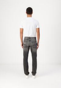 Grå denimjeans med rett ben, baklommer med buet søm, brukt sammen med en tettsittende hvit t-skjorte og hvite sneakers.