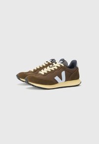 Brown sneakers with a mesh and suede upper, cream laces, a white logo on the side, and a gray accent on the heel. Rubber outsole.