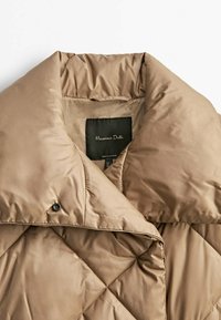 Col col de veste matelassée beige avec fermeture à bouton-pression et étiquette noire portant l'inscription "Massimo Dutti" à l'intérieur de l'encolure.