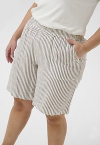 Pantalones cortos a rayas hechos de tela ligera, con cintura y bolsillos laterales, en una combinación de colores beige y marrón con líneas verticales.