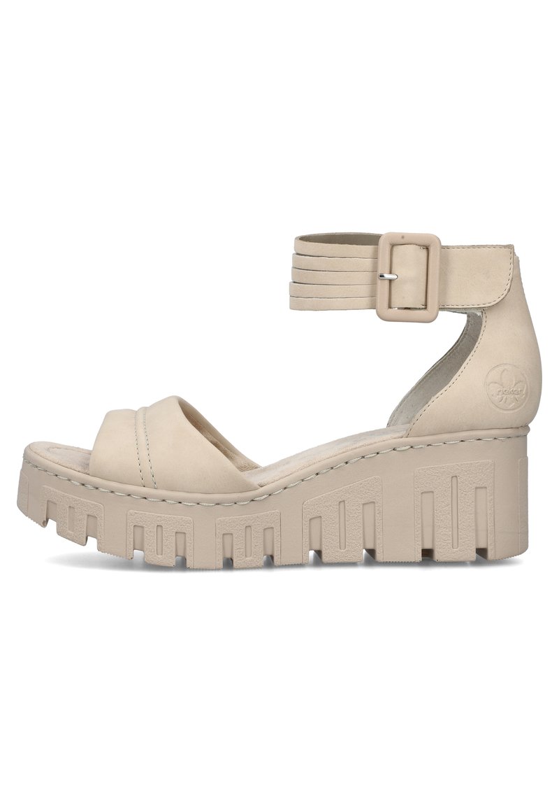 Beige platform sandals with a wide strap over the foot and a buckled ankle strap. Textured wedge sole with geometric cutouts. Soft leather material.