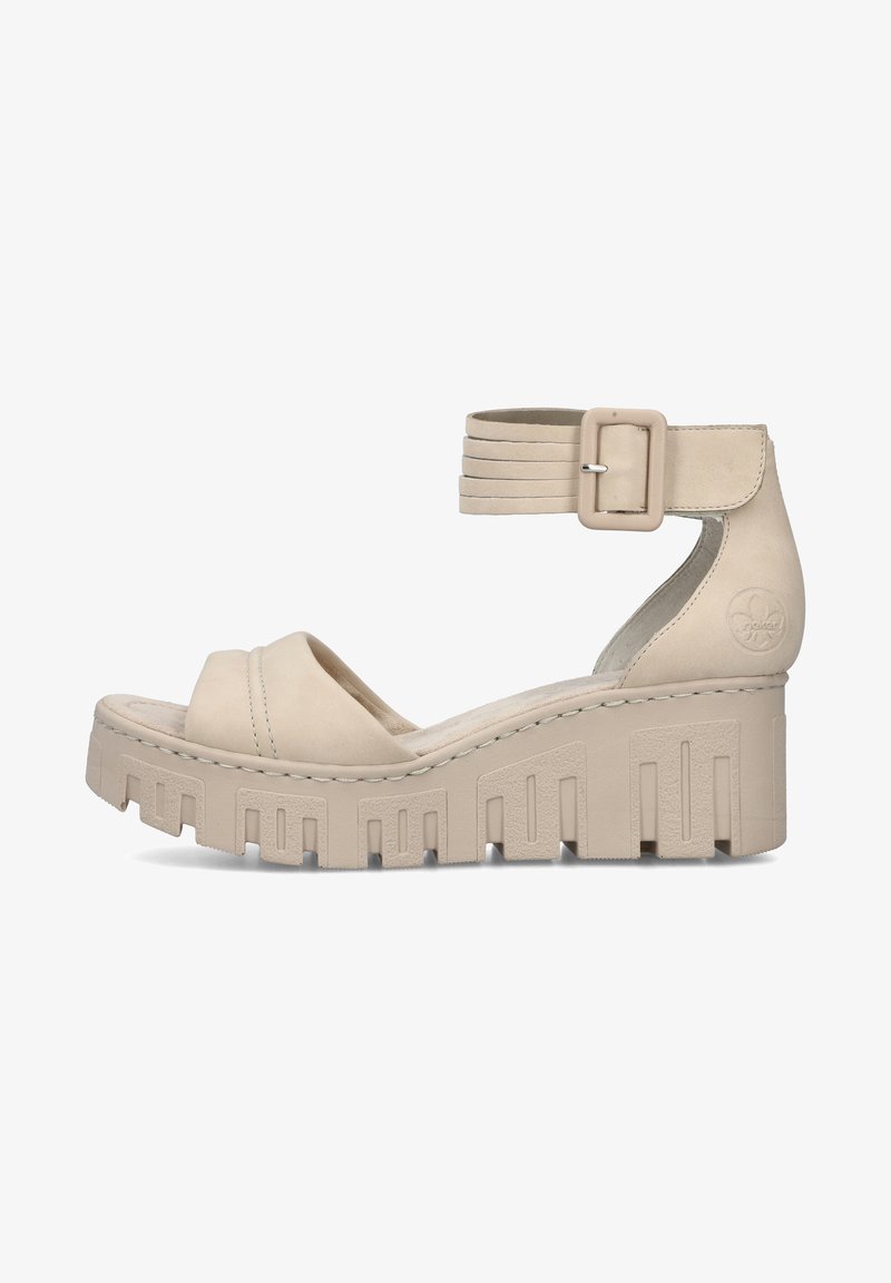 Beige platform sandals with a wide strap over the foot and a buckled ankle strap. Textured wedge sole with geometric cutouts. Soft leather material.