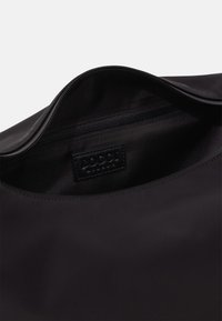 Borsa nera in nylon con chiusura a zip. Presenta una texture liscia e una tasca interna con zip. Etichetta del produttore visibile all'interno.