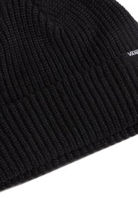 Bonnet en tricot noir avec une texture côtelée et un ourlet retroussé. Présente une petite étiquette de marque sur le côté. Le matériau semble doux et chaud.