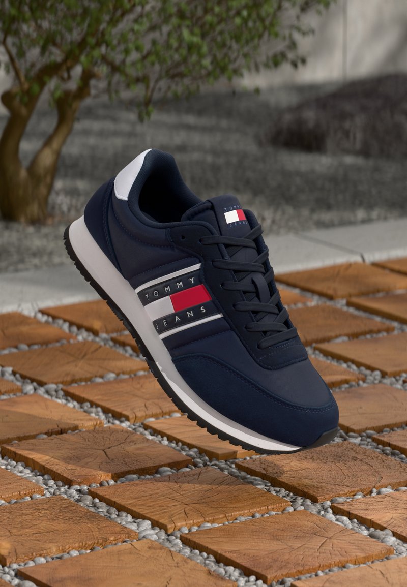 Sneaker blu navy con tomaia in rete e sintetico, dotato di strisce bianche e rosse e dettaglio del logo. Suola bianca imbottita con battistrada testurizzato.